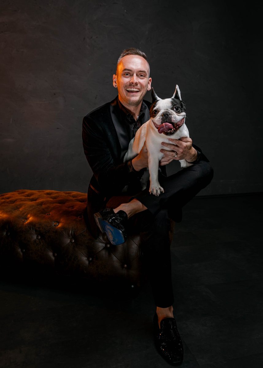 Tyler in a velvet blazer holding his pied French bulldog